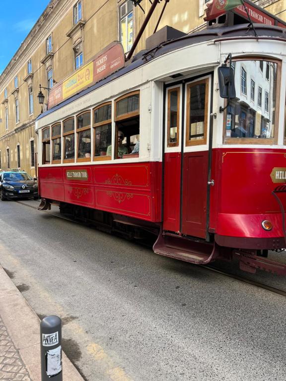 ein roter und weißer Wagen, der eine Straße entlangfährt in der Unterkunft Varandas do chiado - Lisboa in Lissabon