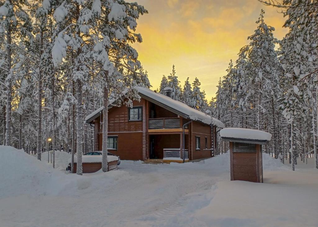 una cabaña de madera en la nieve con árboles en Levi President Suksitie Chalet, en Levi