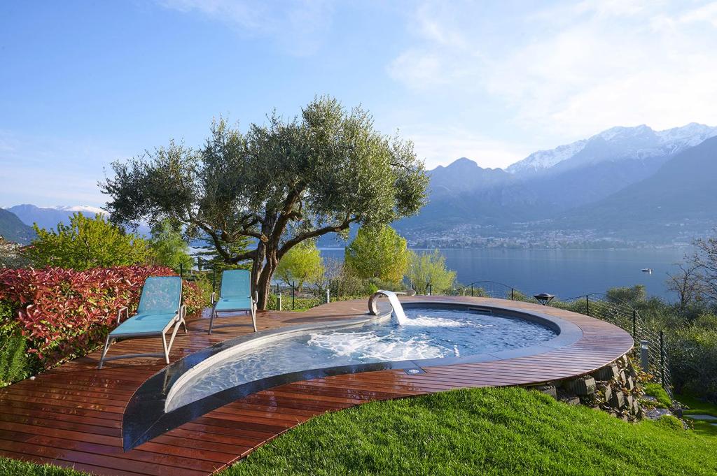 uma piscina com duas cadeiras e uma árvore e água em Villa Costanza- private seasonal warm pool, steam room, sauna-Bellagio Village Residence em Oliveto Lario