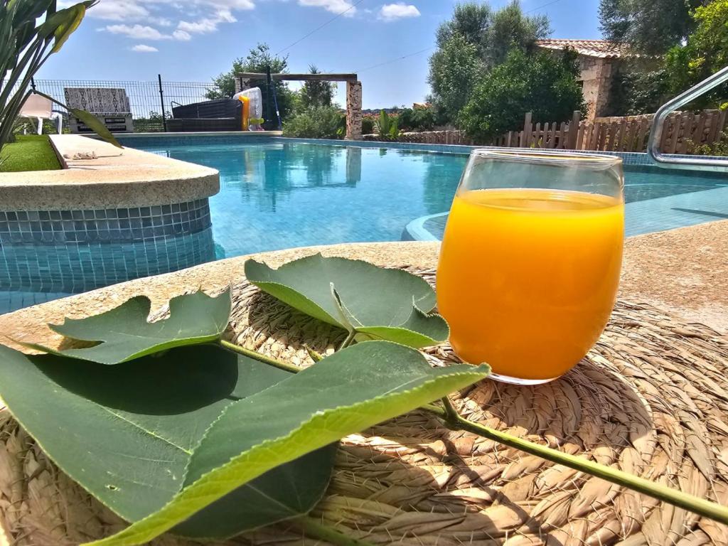 a glass of orange juice sitting on a table next to a pool at Agroturisme Es Racó De Maria in Maria de la Salut