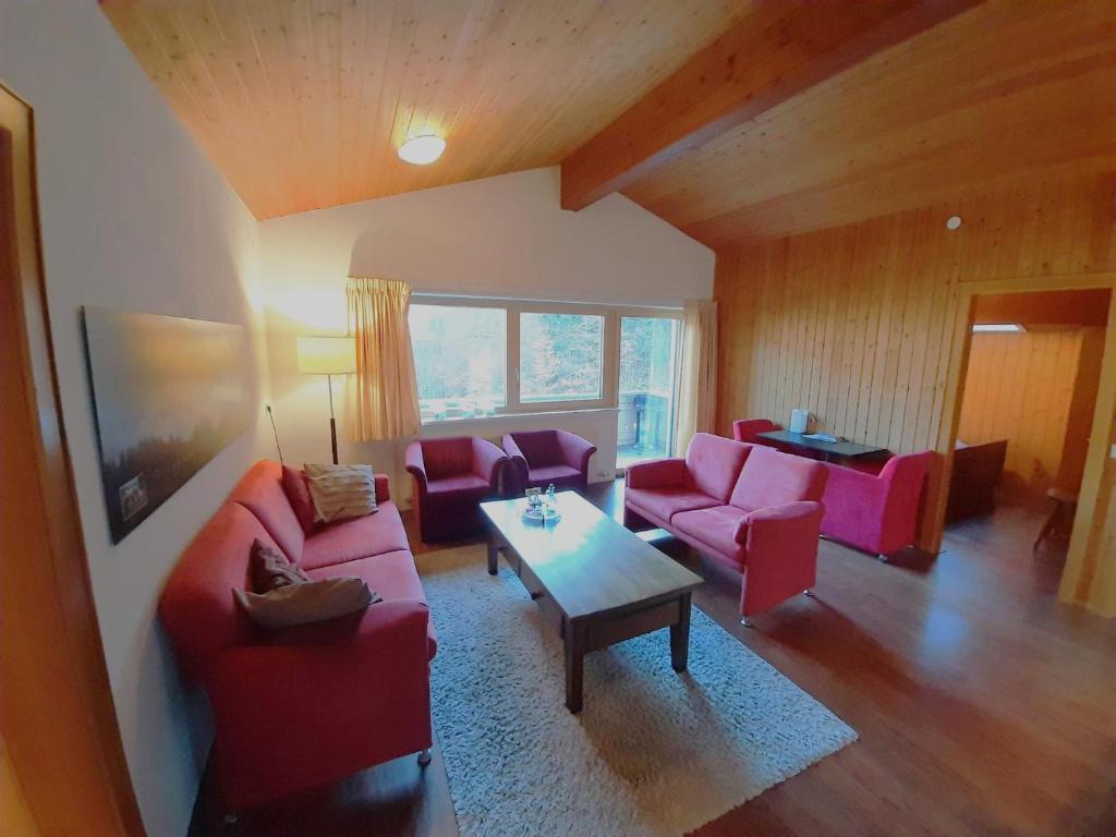 una sala de estar con sofás rojos y una mesa. en Ferienwohnung Tschagguns Top 5, en Schruns