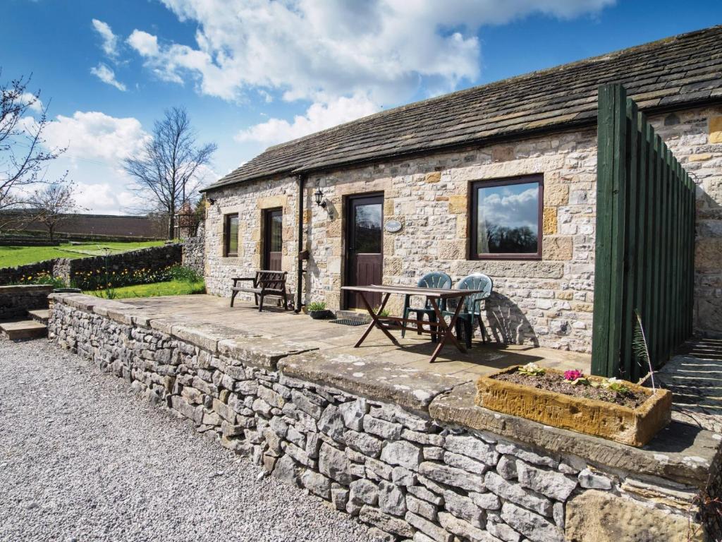 a stone cottage with a table and chairs on a stone wall at 1 Bed in Ashford in the Water PK574 in Great Longstone