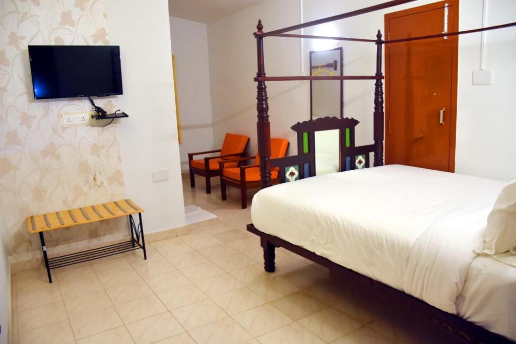 a bedroom with a bed and a tv and chairs at Vacation villa in Yercaud