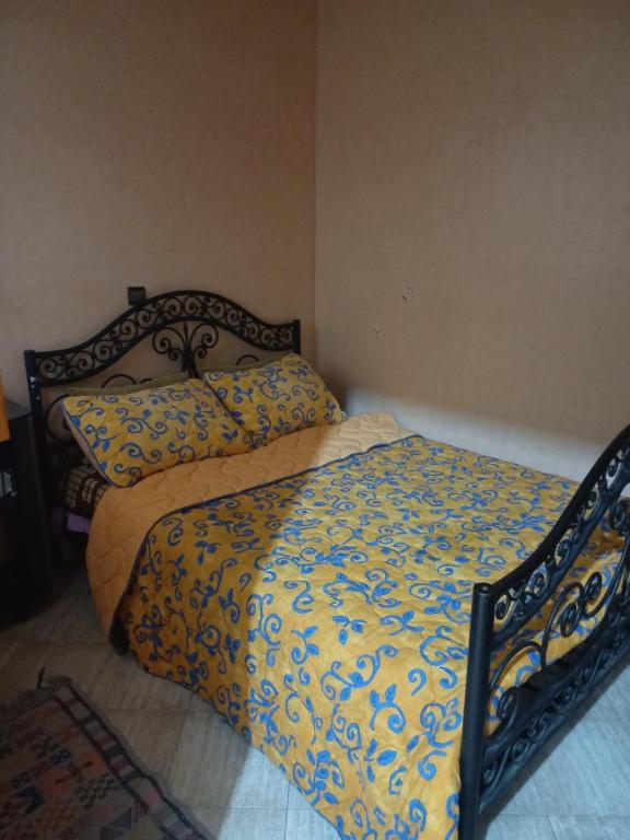 a bed with a yellow and blue comforter in a bedroom at Apartement privé in Taroudant