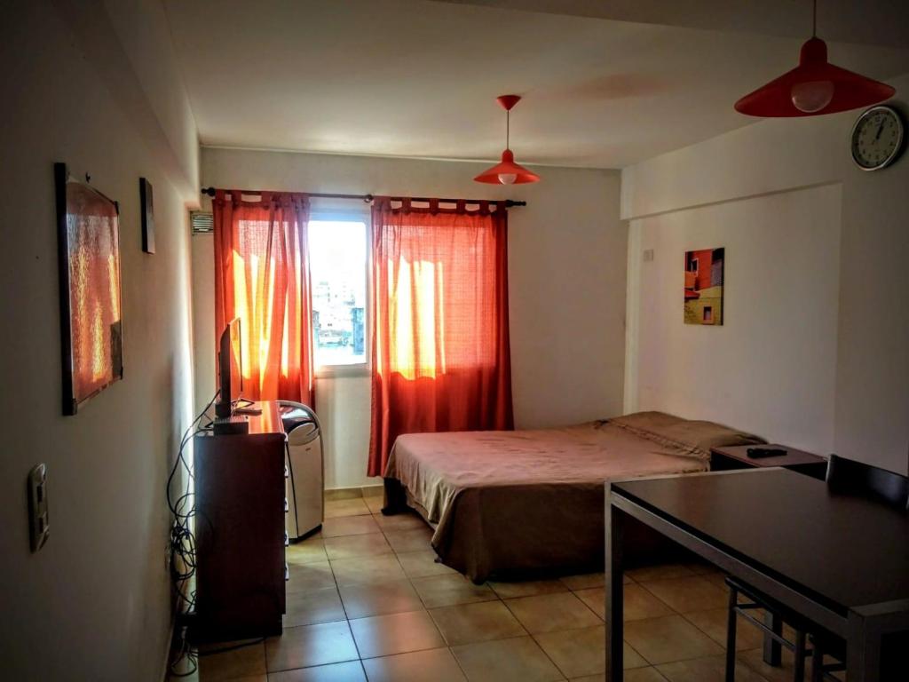 a bedroom with a bed and a window with red curtains at Depto En Rosario in Rosario