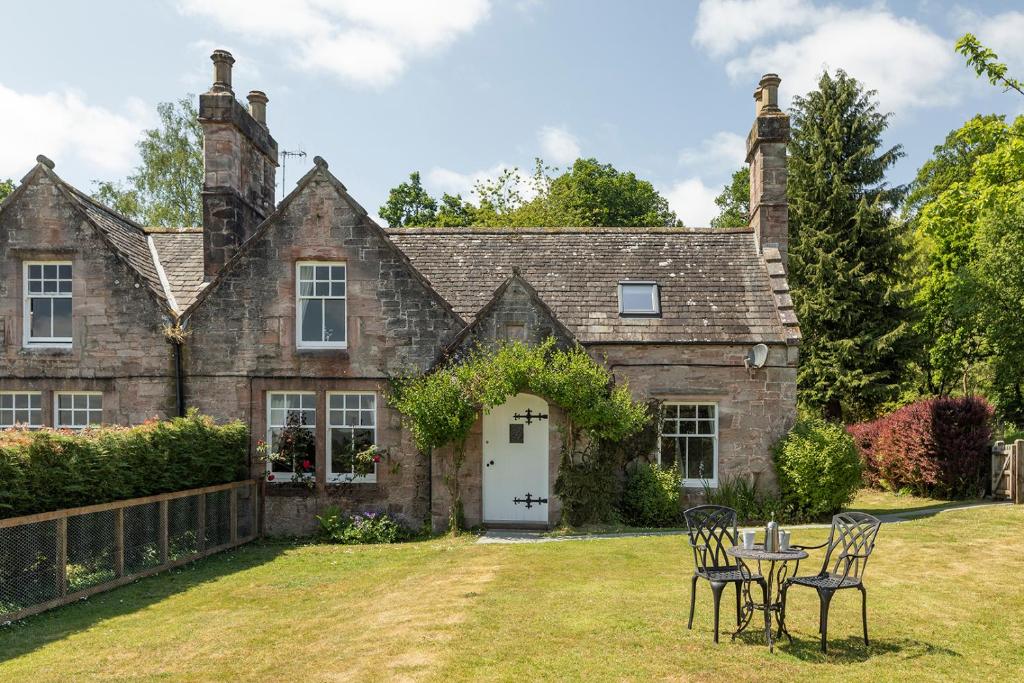 an old stone house with a table and chairs at Drumlanrig Mains Cottage in Thornhill