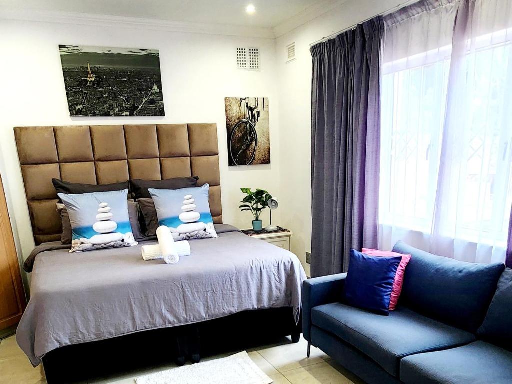 a bedroom with a bed and a blue couch at 7 on Mendoza in Durban
