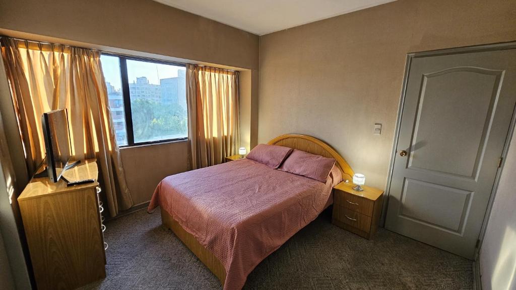 um pequeno quarto com uma cama e uma janela em Edificio Presidente em Mendoza