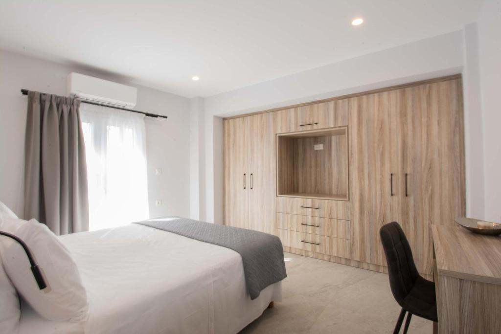 een slaapkamer met een wit bed, een bureau en een raam bij Utopia Residences "by Checkin" in Chersonissos