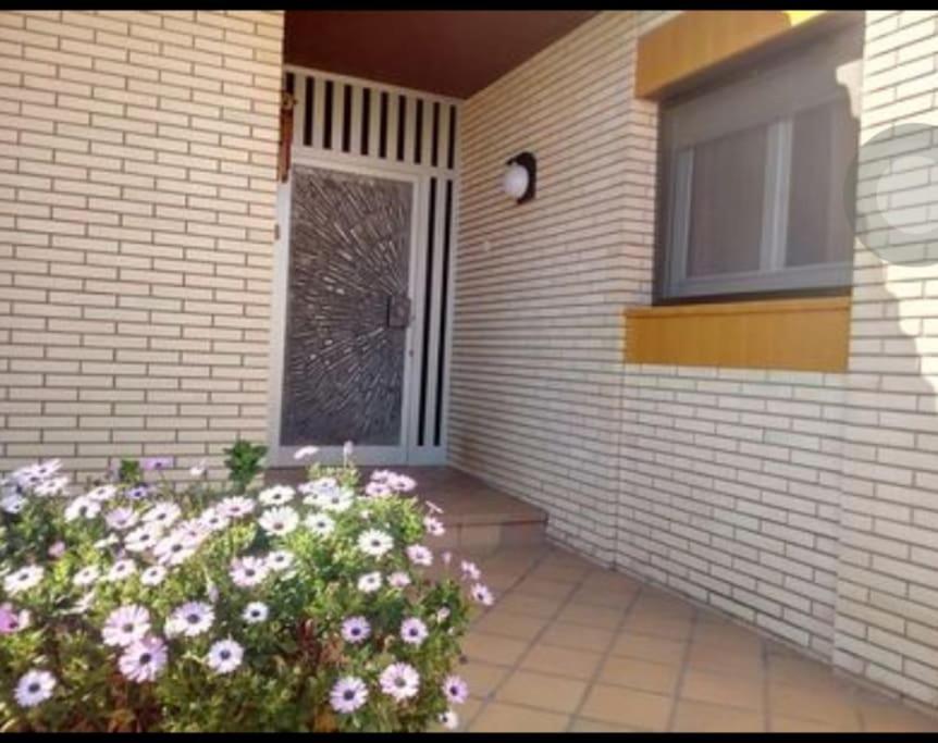 eine Eingangstür eines Hauses mit einem Fenster und Blumen in der Unterkunft Casa Parra in Deltebre
