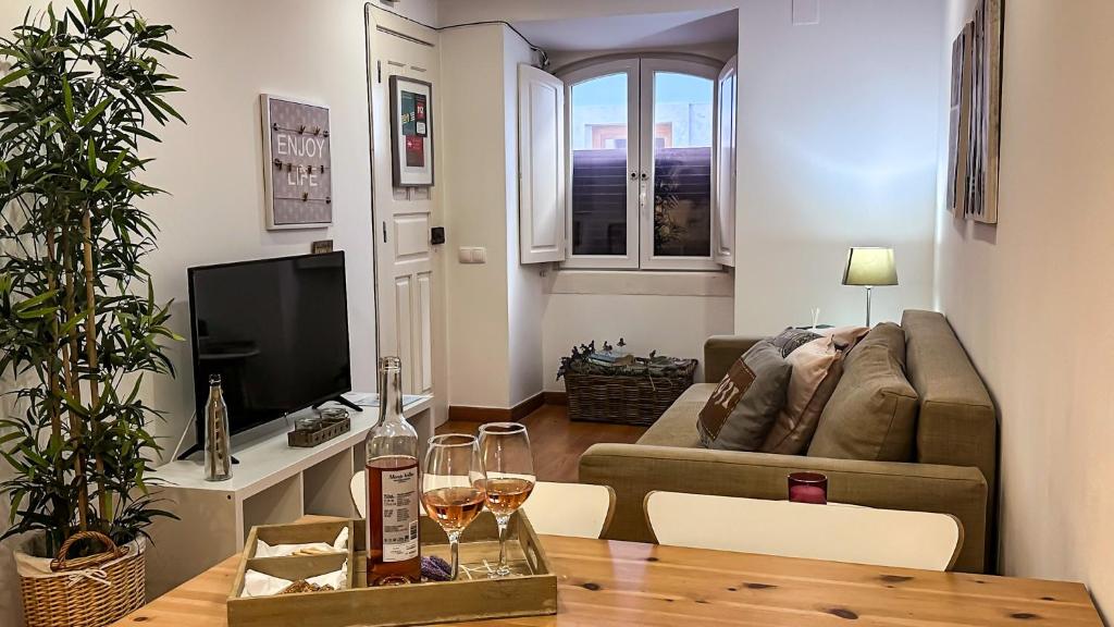 een woonkamer met een bank en een tafel met wijnglazen bij T2 Apartment -Cascais center - 100m from beach in Cascais