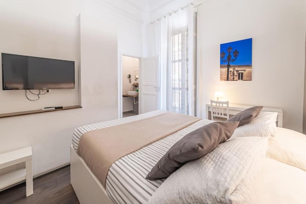 Un dormitorio blanco con una cama y un televisor de pantalla plana. en Villa Bellini Luxury Home, en Catania