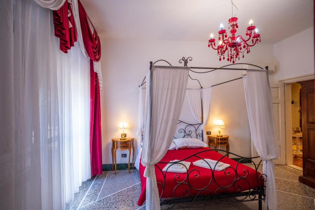 1 dormitorio con cama roja y lámpara de araña en BBC Christian Bed & Breakfast, en Pisa