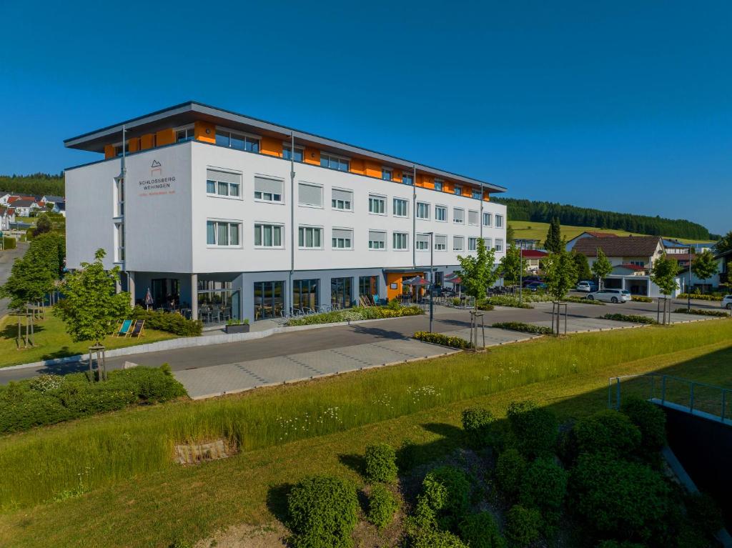 a large white building with a parking lot at Hotel Schlossberg Wehingen in Wehingen
