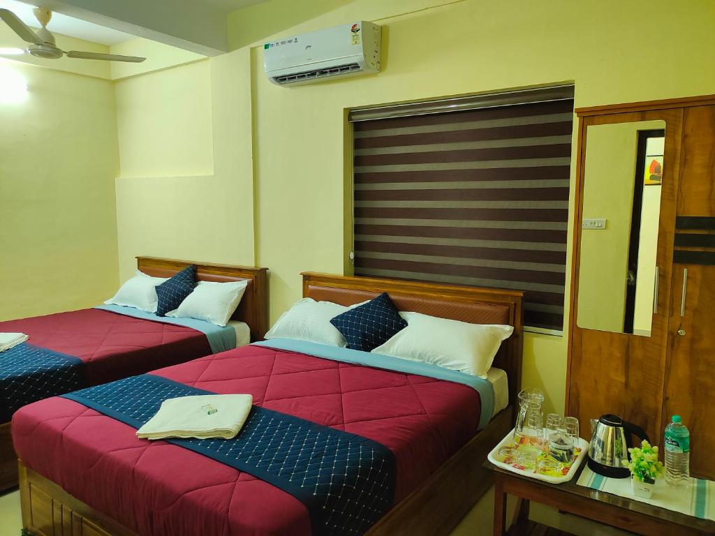 1 Schlafzimmer mit 2 Betten mit roter Bettwäsche und einem Tisch in der Unterkunft Mystique Inn Wayanad in Vythiri
