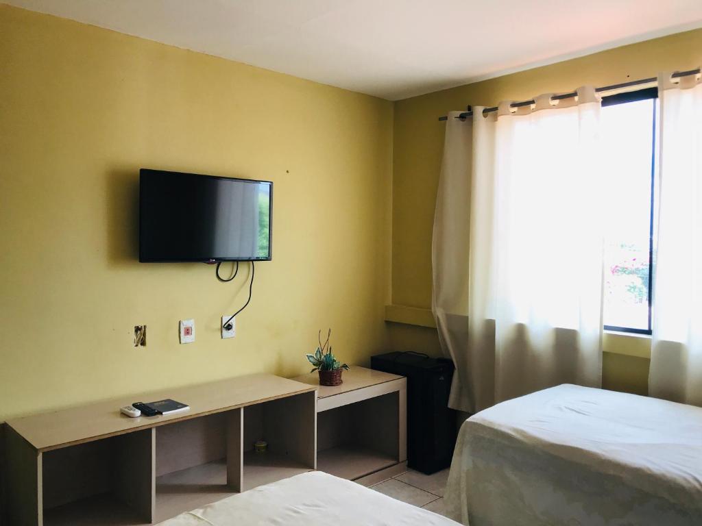 ペトロリーナにあるPousada Cantinho do Sossegoのベッド2台、壁掛けテレビが備わる客室です。
