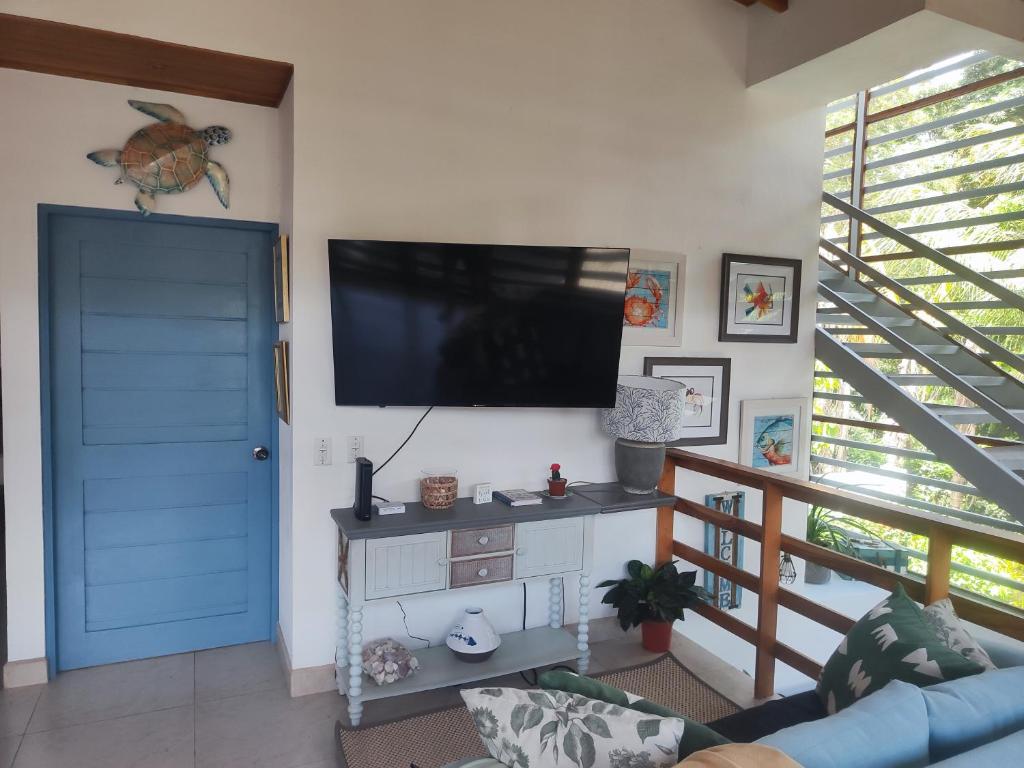 ein Wohnzimmer mit einer blauen Tür und einem Flachbild-TV in der Unterkunft Casa del sol in Bejuco