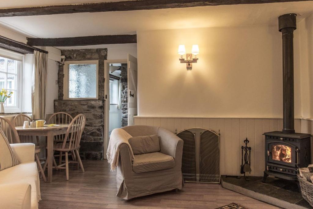 a living room with a fireplace and a chair at The Linhay in Hartland
