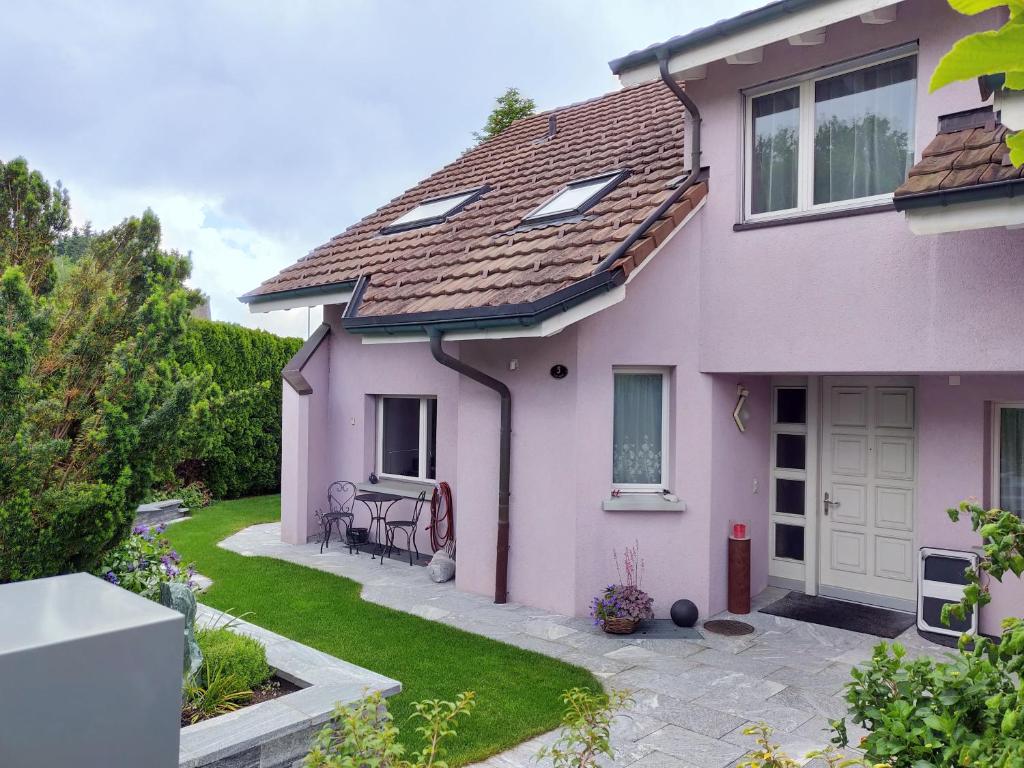 a pink house with a patio and yard at MENBERGS HARMONY HOMESTAY in Hildisrieden