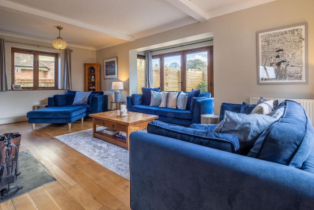 uma sala de estar com sofás azuis e uma mesa em Monkey Puzzle Cottage em Snettisham