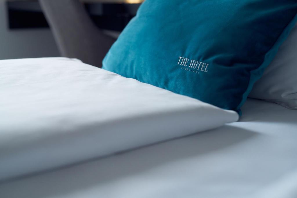 a bed with a blue pillow on top of it at The Hotel Ljubljana in Ljubljana
