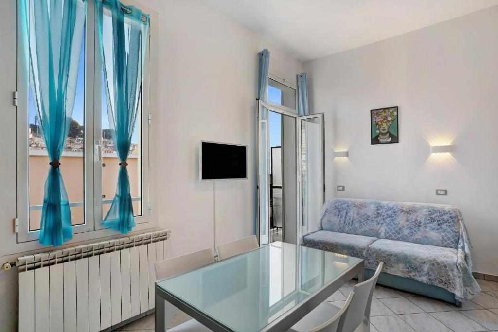un soggiorno con tavolo in vetro e divano di Frida apartments a Sanremo