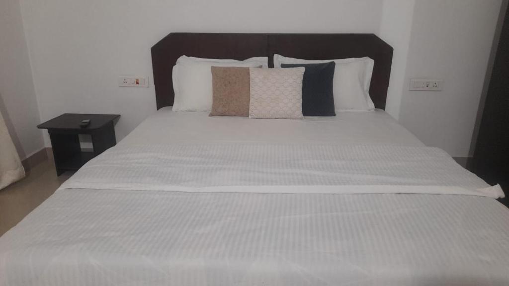 sypialnia z dużym białym łóżkiem z czarnym zagłówkiem w obiekcie INAS Guest House w mieście Canacona