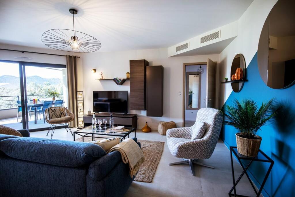 un salon avec un canapé bleu et des chaises dans l'établissement Appt 2 chambres, neuf proche de toutes commodités., à Porto-Vecchio