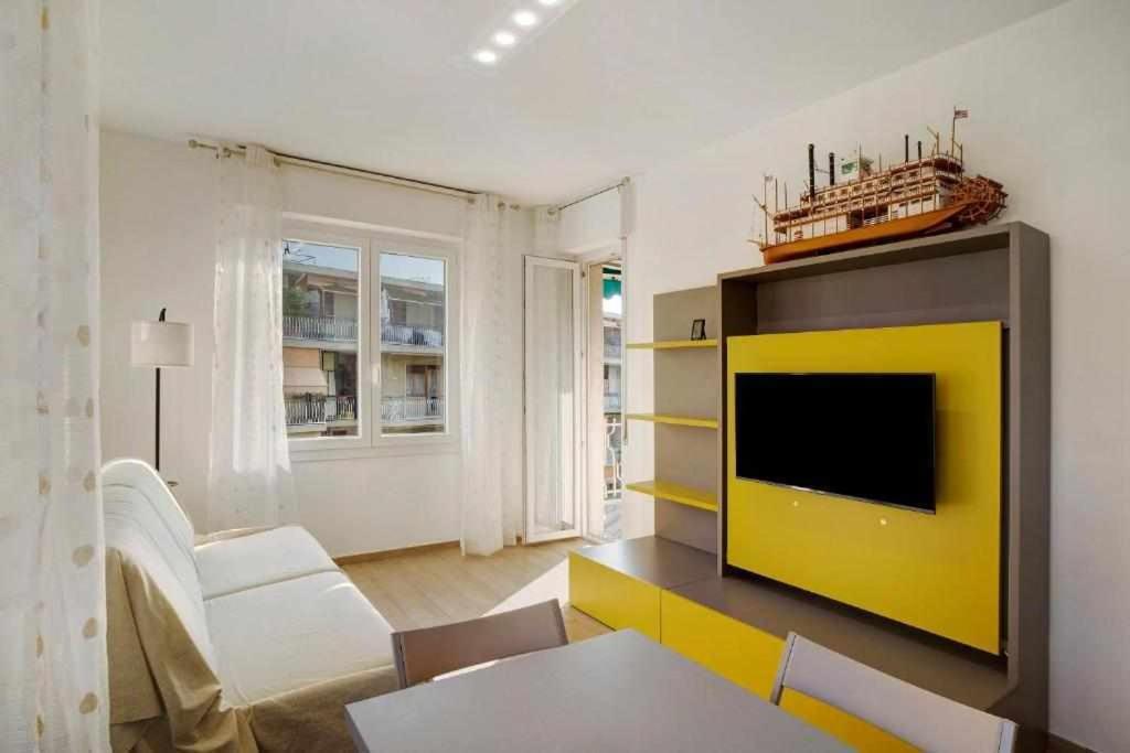 サンレモにあるNinfea apartmentsの黄色の壁のリビングルーム(テレビ付)