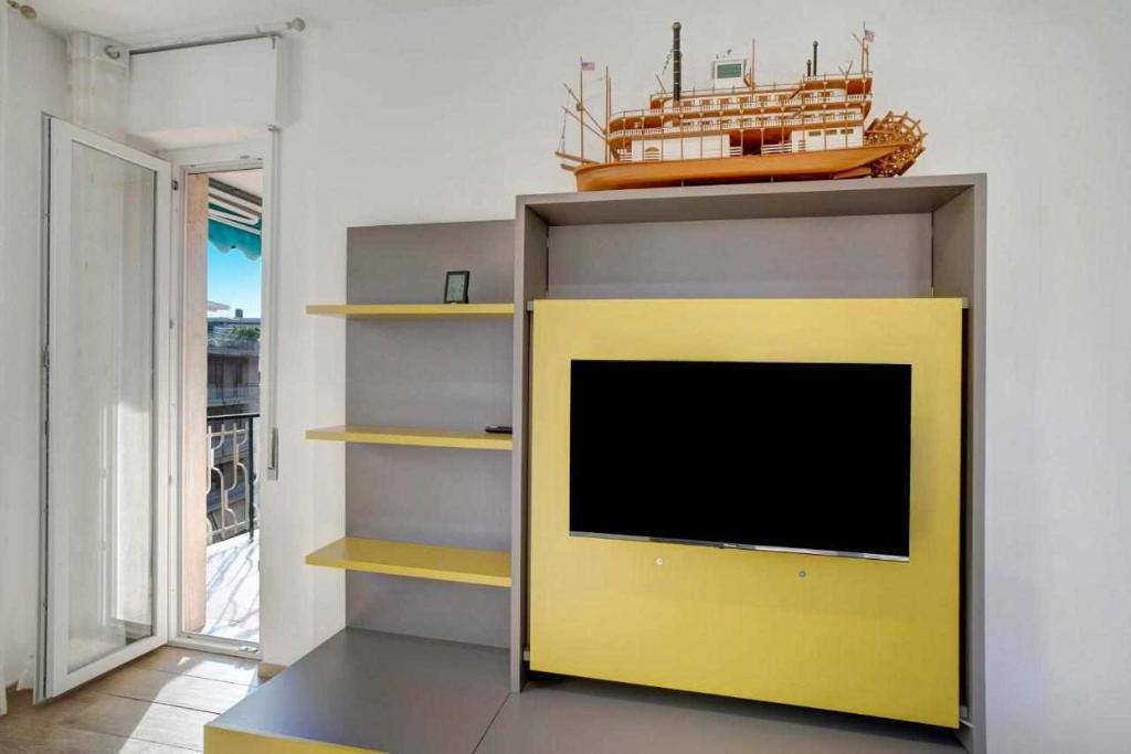 a tv in a living room with a yellow wall at Ninfea apartments in Sanremo