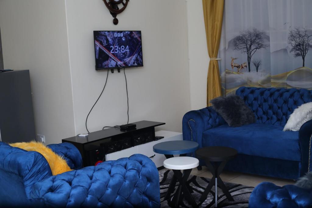 a living room with two blue couches and a tv at pettan Appartment in Kampala