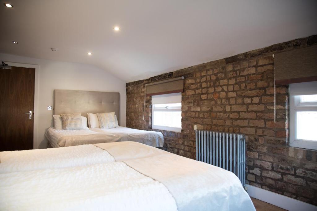 a bedroom with two beds and a brick wall at Richmond Apartment in Liverpool