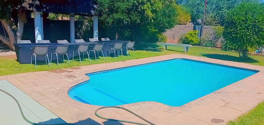 een blauw zwembad met stoelen en een tafel bij Boontjieskraal in Kimberley