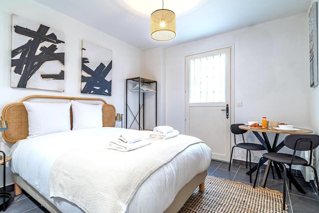 une chambre avec un grand lit blanc et une table dans l'établissement Studio équipé à 5 minutes de Paris - Montreuil -II, à Montreuil