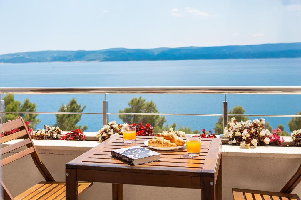 a wooden table with a plate of food on a balcony at Villa Jolara With Pool - Deluxe Suite 13 in Mimice