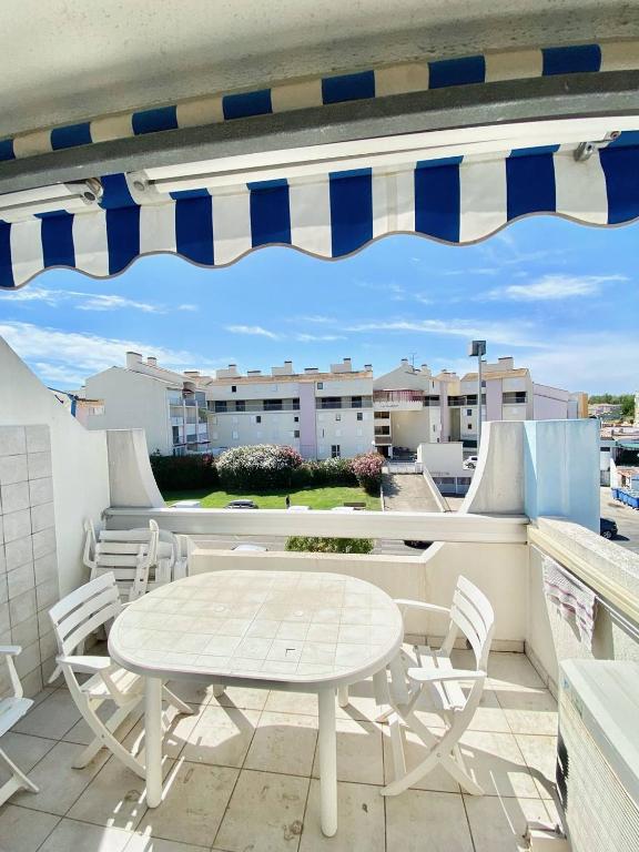 un patio avec une table et des chaises sur un balcon dans l'établissement APPARTEMENT 1 CHAMBRE, 6 PERSONNES DANS RESIDENCE AVEC PISCINES, au Grau-du-Roi