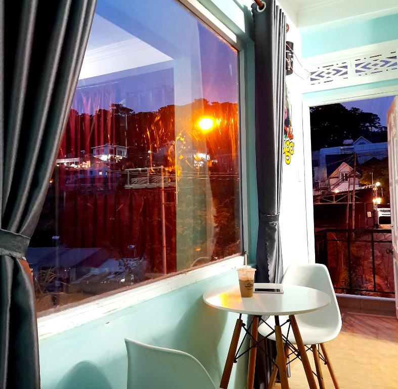 a table and chairs in front of a window at Hugo's Family in Da Lat