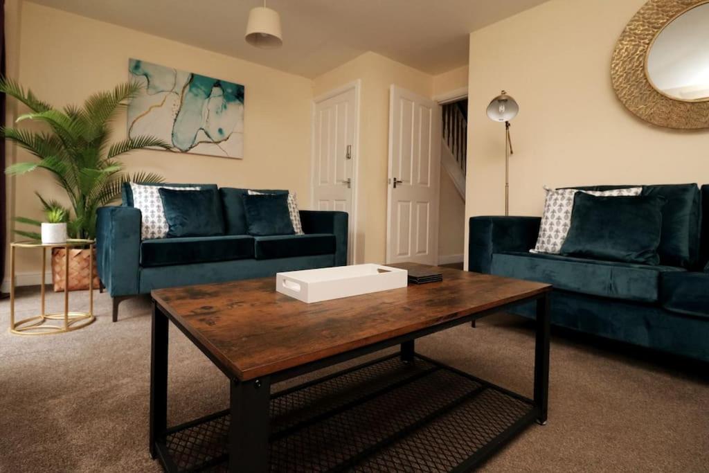uma sala de estar com sofás azuis e uma mesa de centro em Modern 4 Bed House with Parking em Swadlincote
