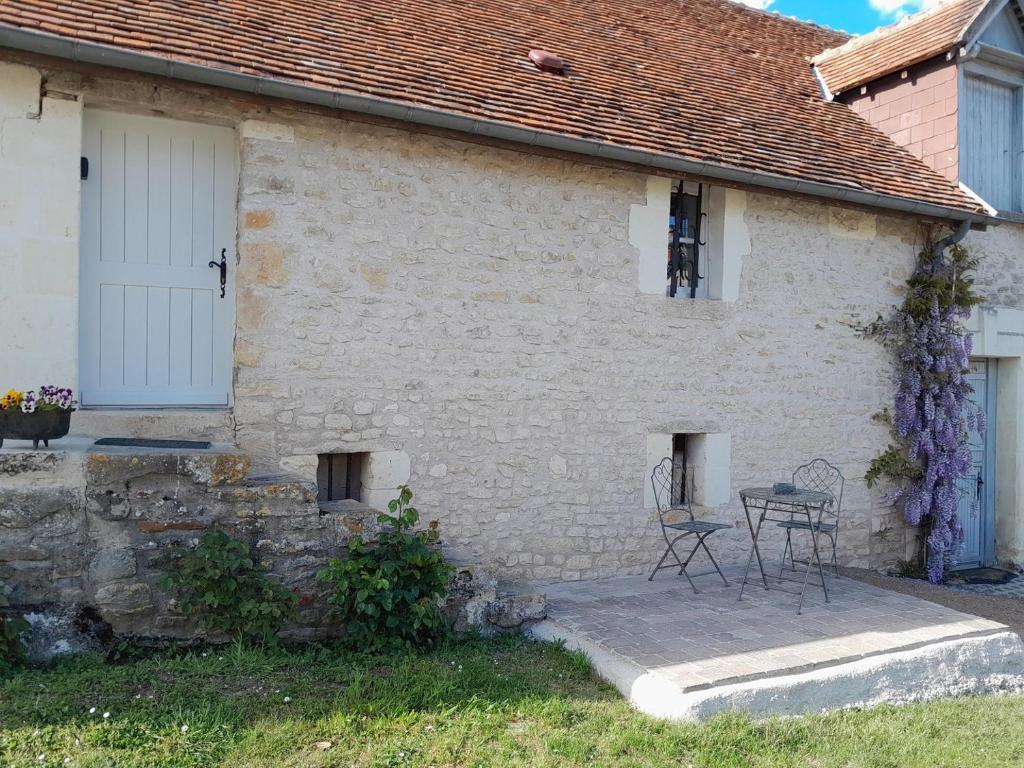 Charmante petite maison 2 personnes في Chambourg-sur-Indre: منزل من الطوب الأبيض مع طاولة وكراسي في الخارج