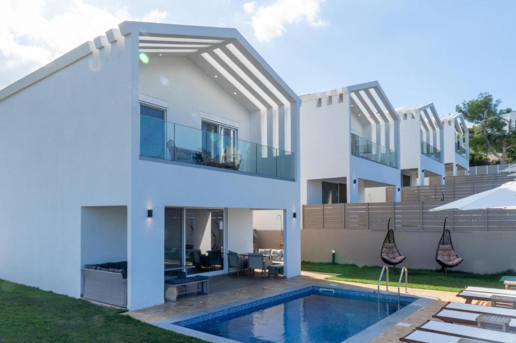 a white house with a swimming pool and a patio at Diamond Nevelo Quality Villas in Gerani