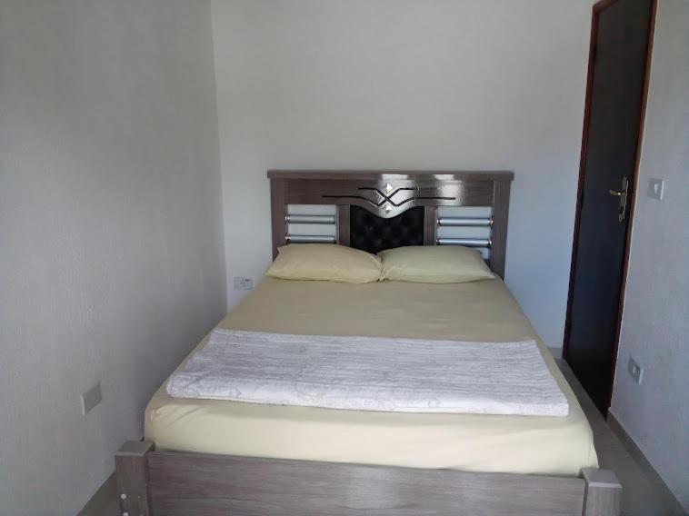 1 cama con cabecero de madera en un dormitorio en Suíte em Caraguá, en Caraguatatuba