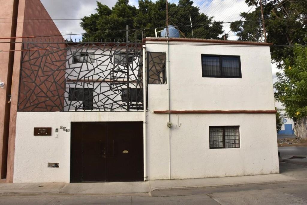 un edificio blanco con una puerta negra en una calle en Casa Gris Alemán, en Oaxaca City