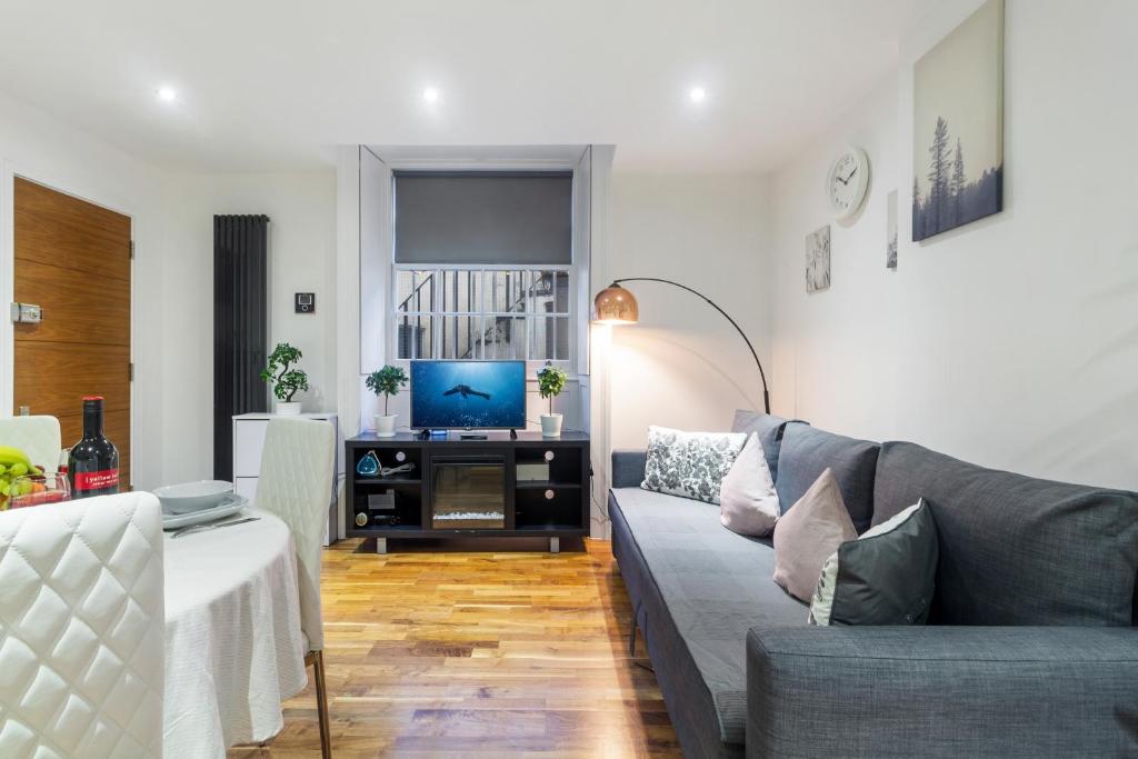 a living room with a couch and a television at Paddington Gardens in London
