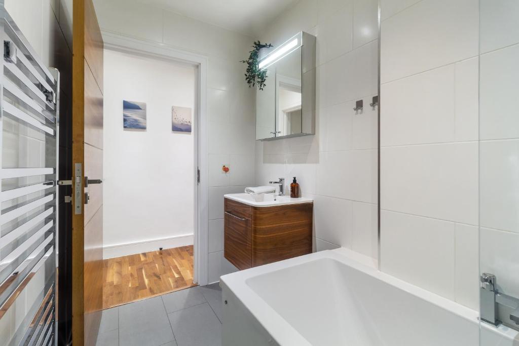 a white bathroom with a sink and a mirror at Paddington Gardens in London