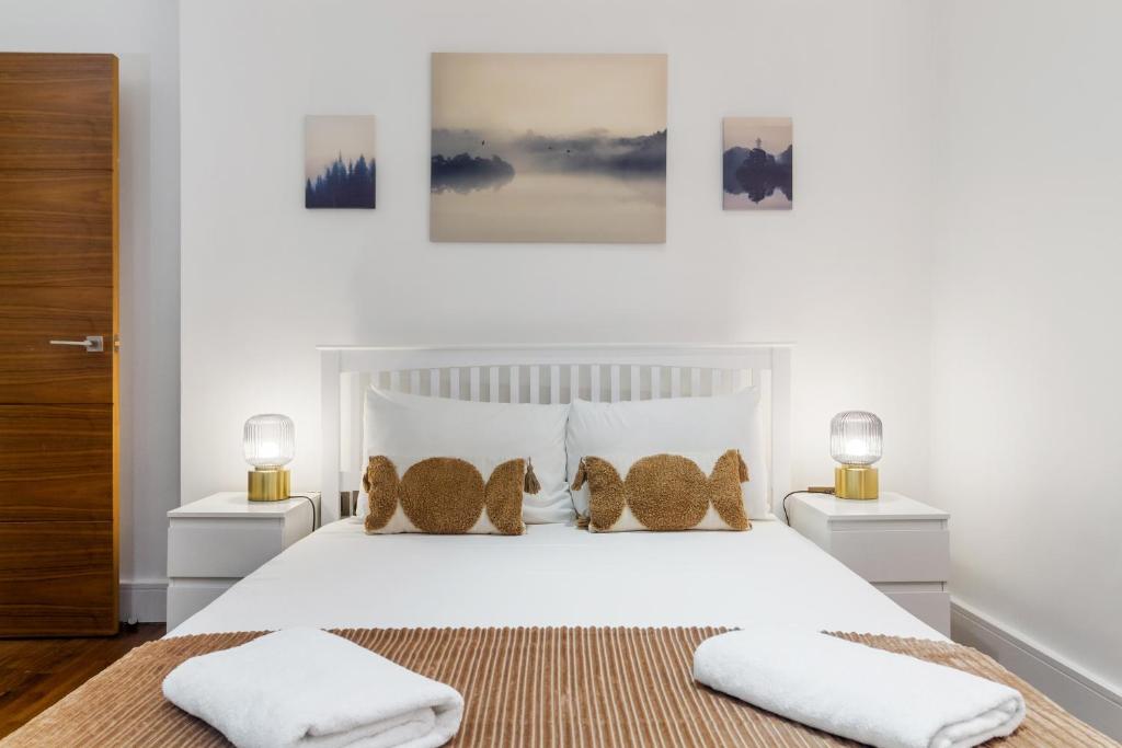 a bedroom with a white bed with two night stands at Paddington Gardens in London