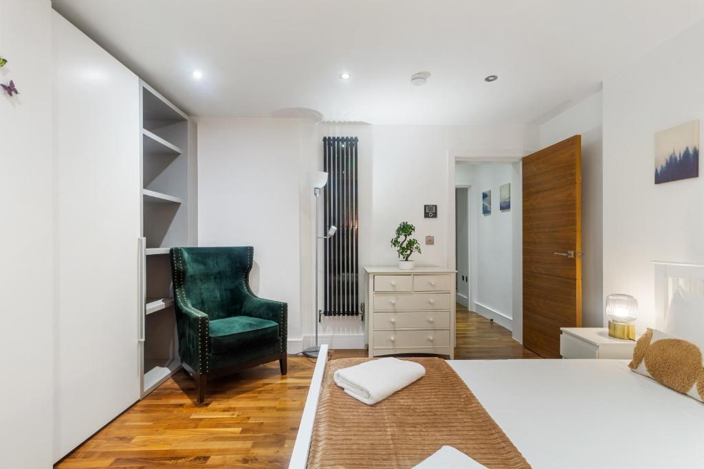 a bedroom with a king sized bed and a green chair at Paddington Gardens in London