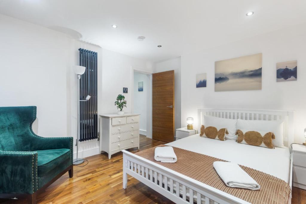 a bedroom with a white bed and a green chair at Paddington Gardens in London