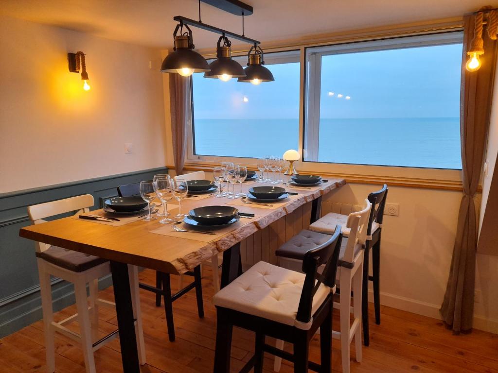 uma mesa de jantar com cadeiras e uma grande janela em "Le JUGUILI" 46m2 en front de Mer - 4 personnes - animaux OK - Entièrement rénové - Haut de gamme - wifi em Mers-les-Bains