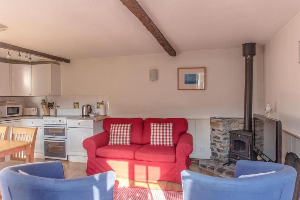 a living room with a red couch and a kitchen at The Stables in Hartland