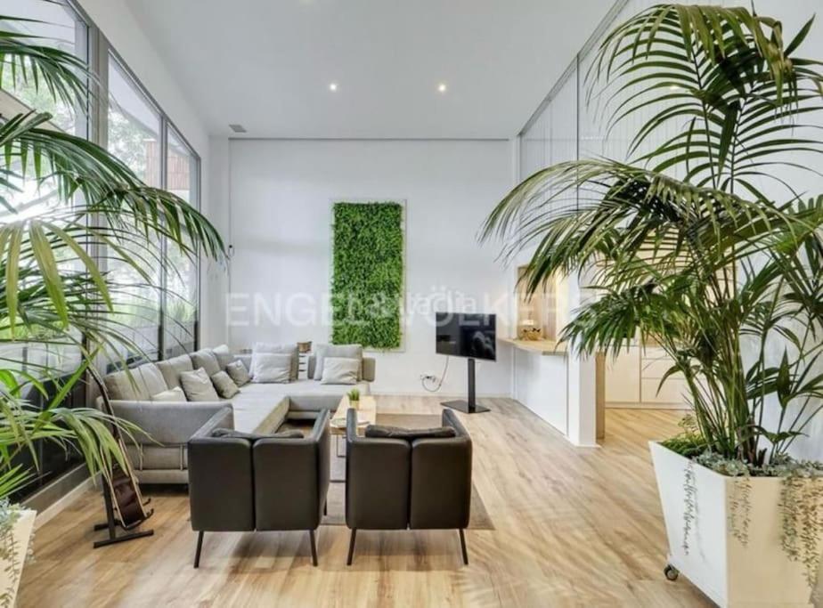 a living room with a couch and two palm trees at apartamento exclusivo muy cerca ciudad Barcelona in Badalona